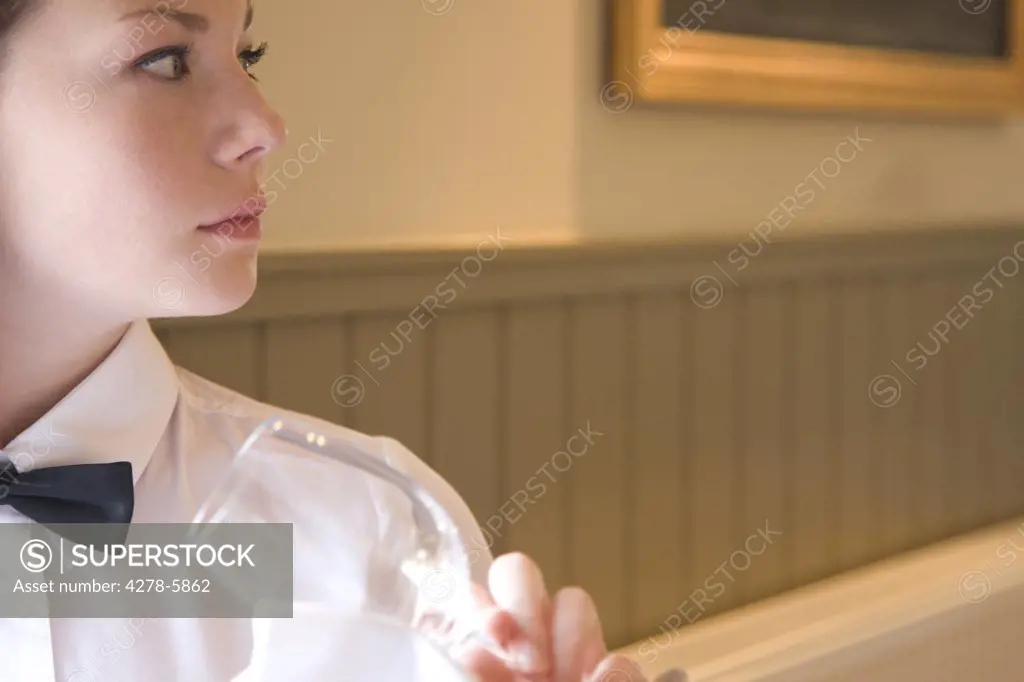 Waitress holding a wine glass looking to one side