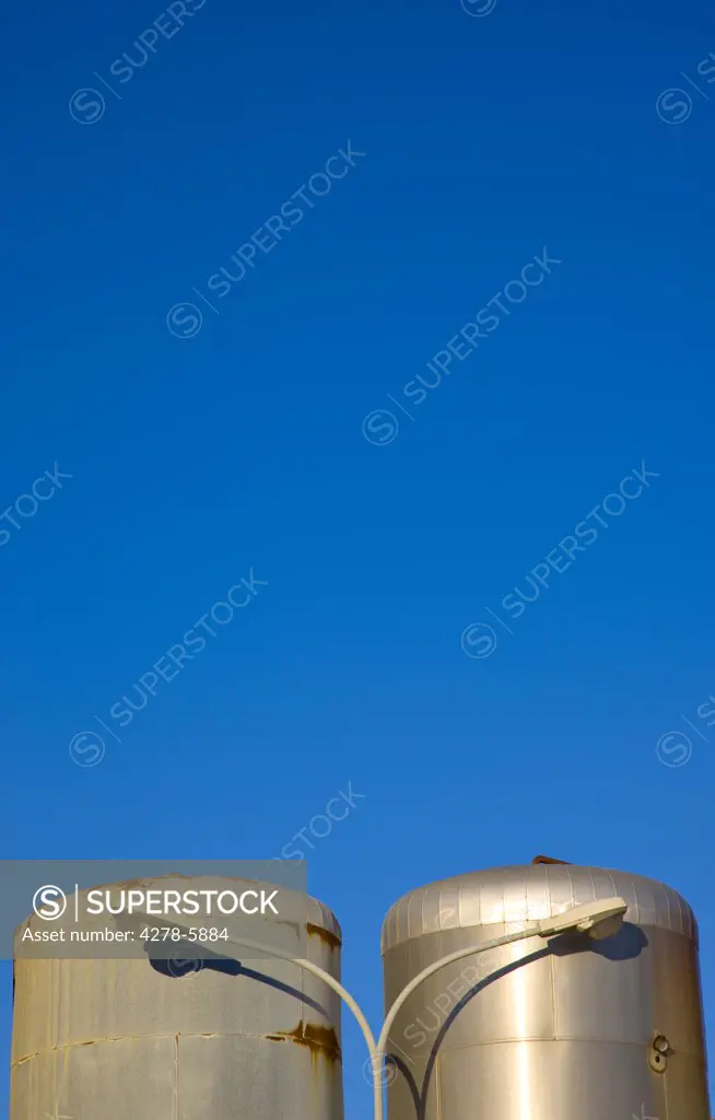 Metal storage tanks and lamp post against a cloudless blue sky
