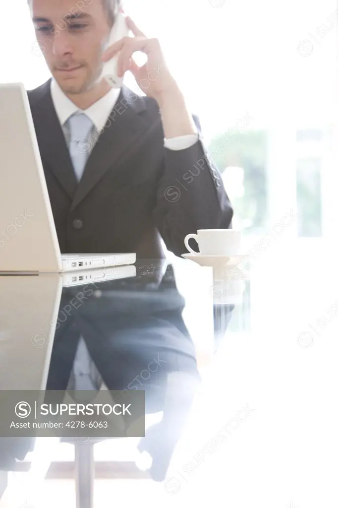 Young businessman talking on the phone behind a laptop computer