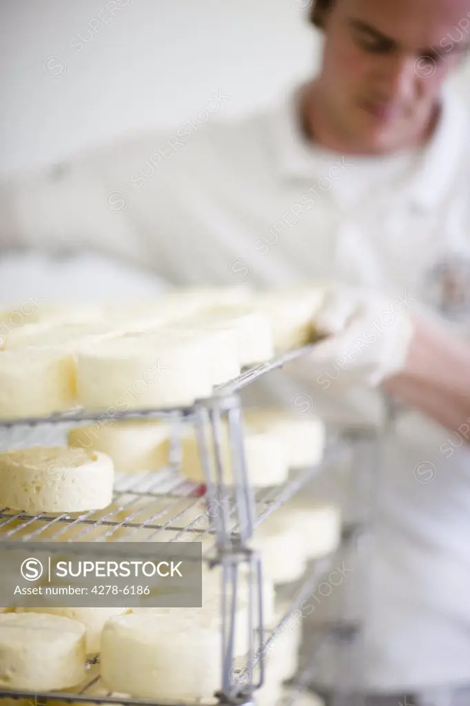 Man lifting up rack lined up with cheeses