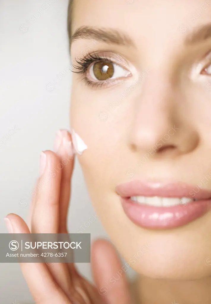 Extreme close up of a woman applying cosmetic cream