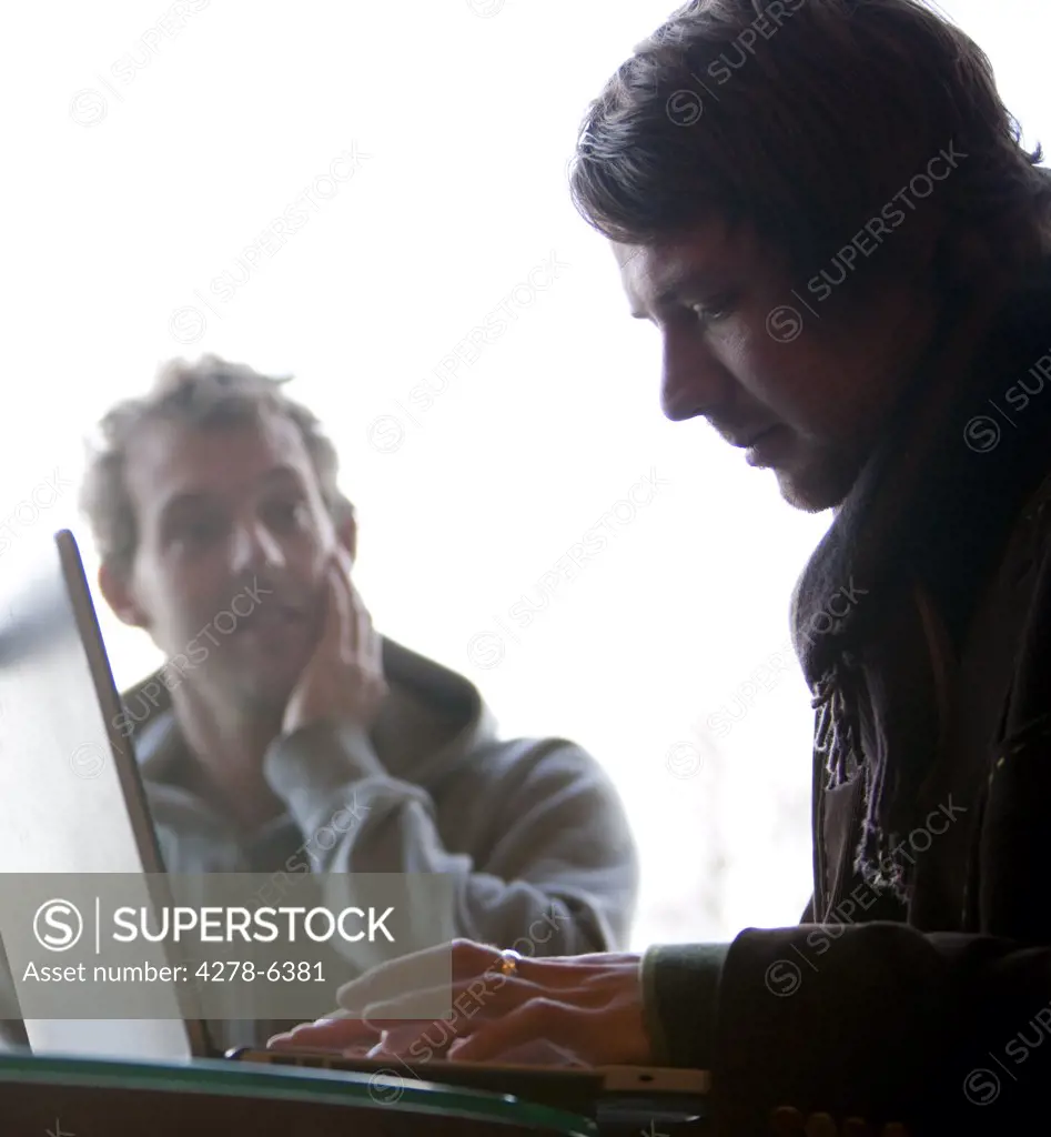 Two men using a laptop