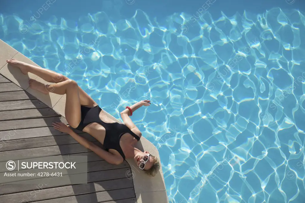 Elevated view of a woman sunbathing on the edge of a swimming pool