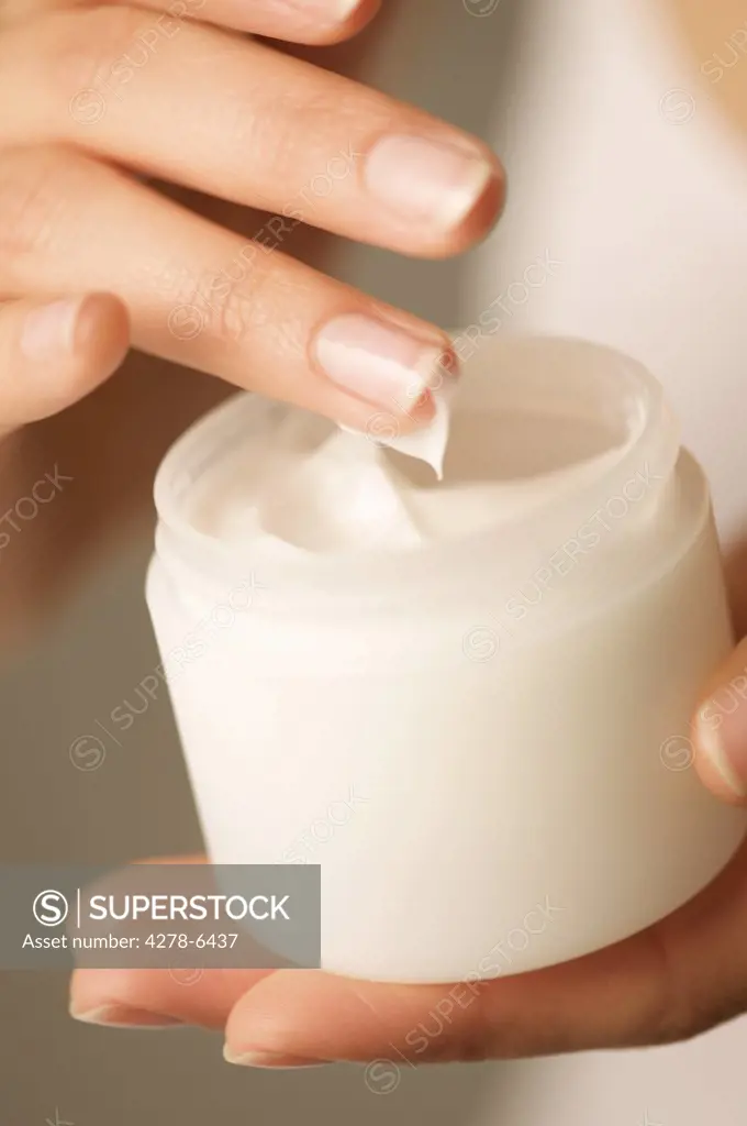 Close up of a woman's hands holding an open jar of cosmetic cream