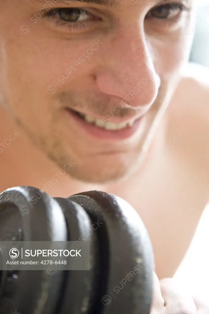 Close up of young man's face lifting dumbbell
