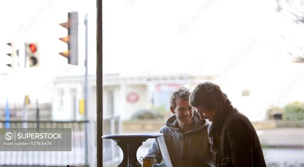 Two men using a laptop in a cafe