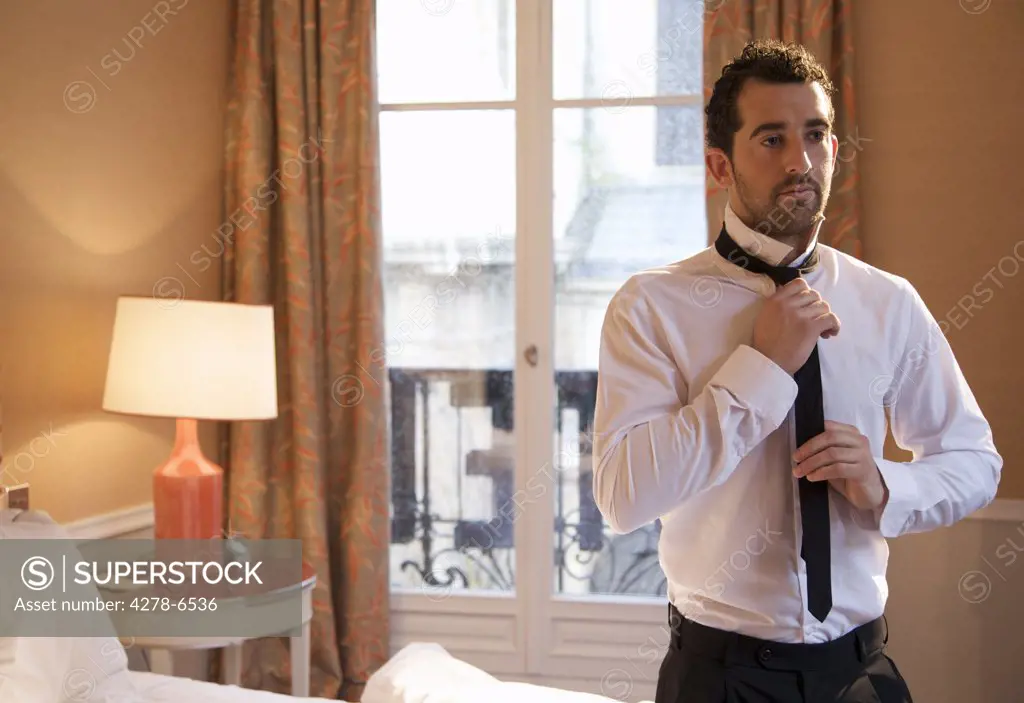 Businessman in hotel room tying his tie