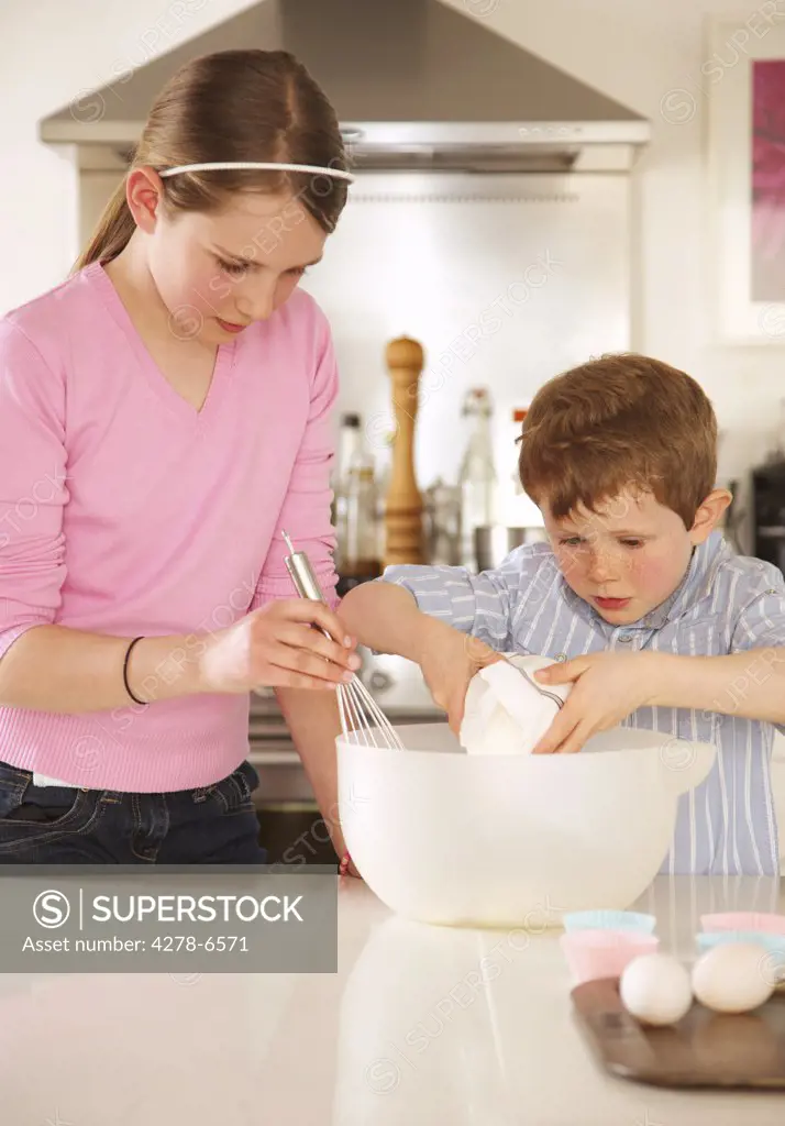 Girl and young boy preparing cupcakes