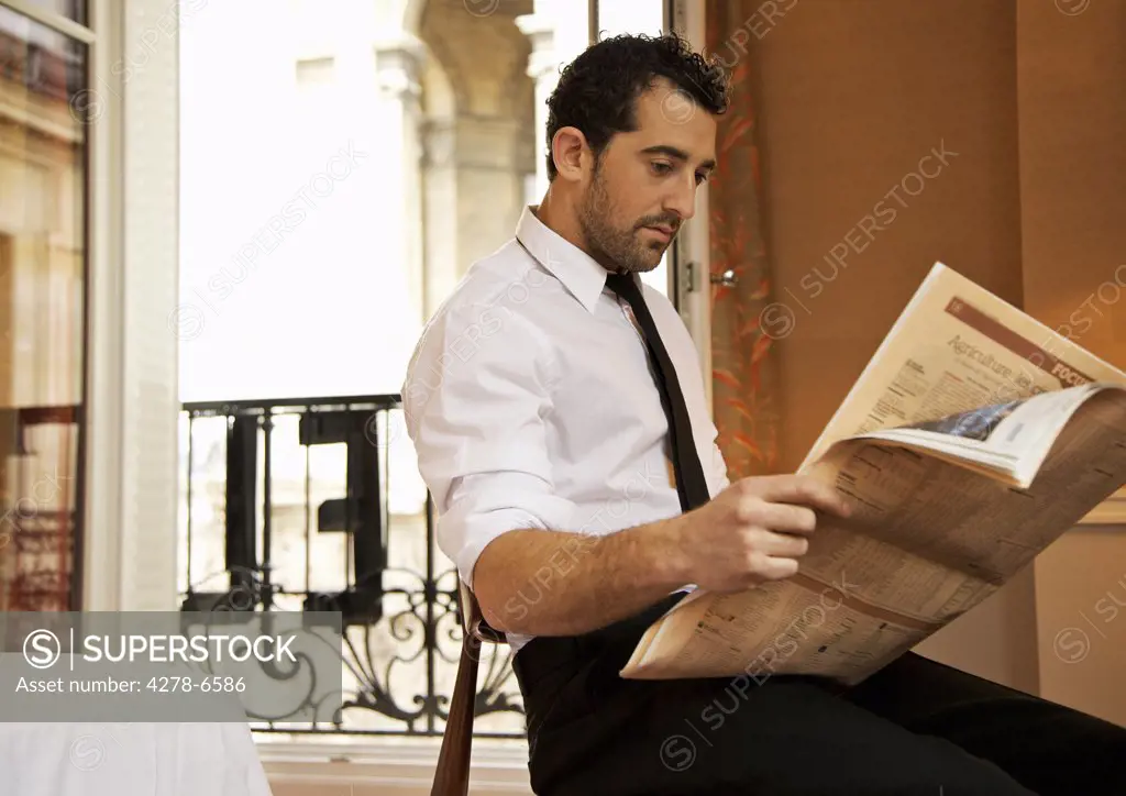 Businessman in hotel room reading newspaper