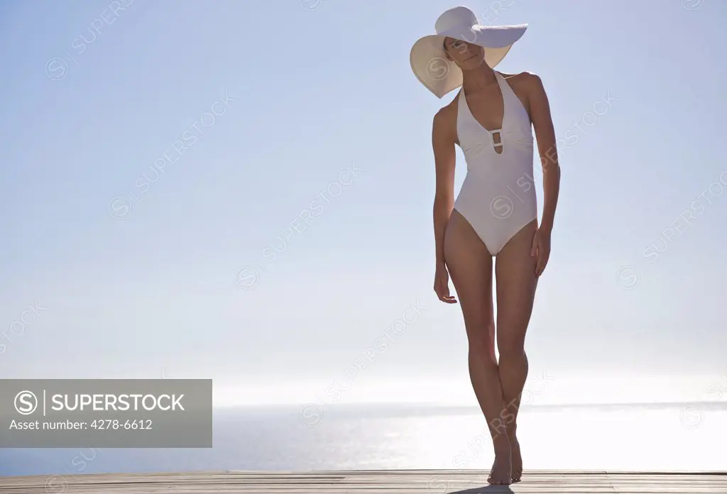 Woman in white hat and swimsuit standing on a sun deck