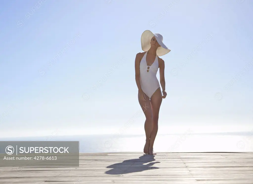 Woman in white hat and swimsuit standing on a sun deck