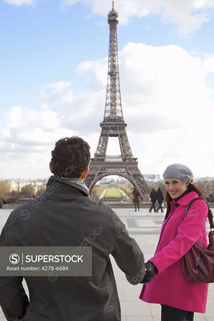 Couple holding hands in front of the Eiffel Tower
