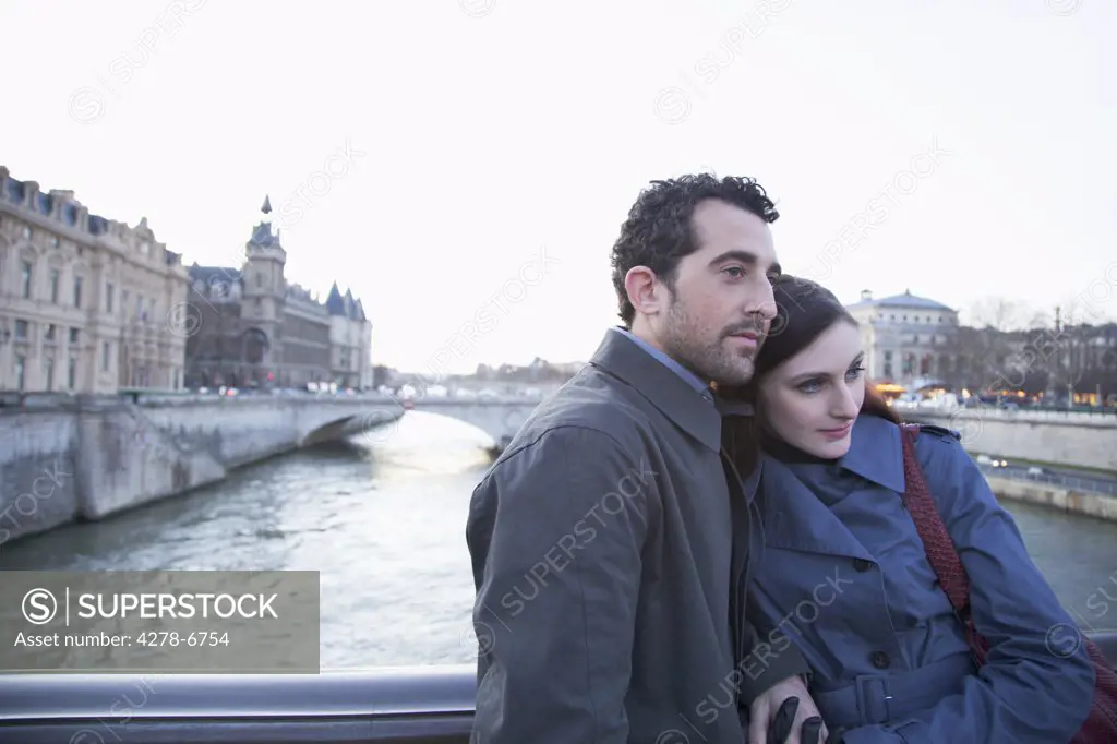Young couple hugging on a bridge over the Seine river, Paris, France