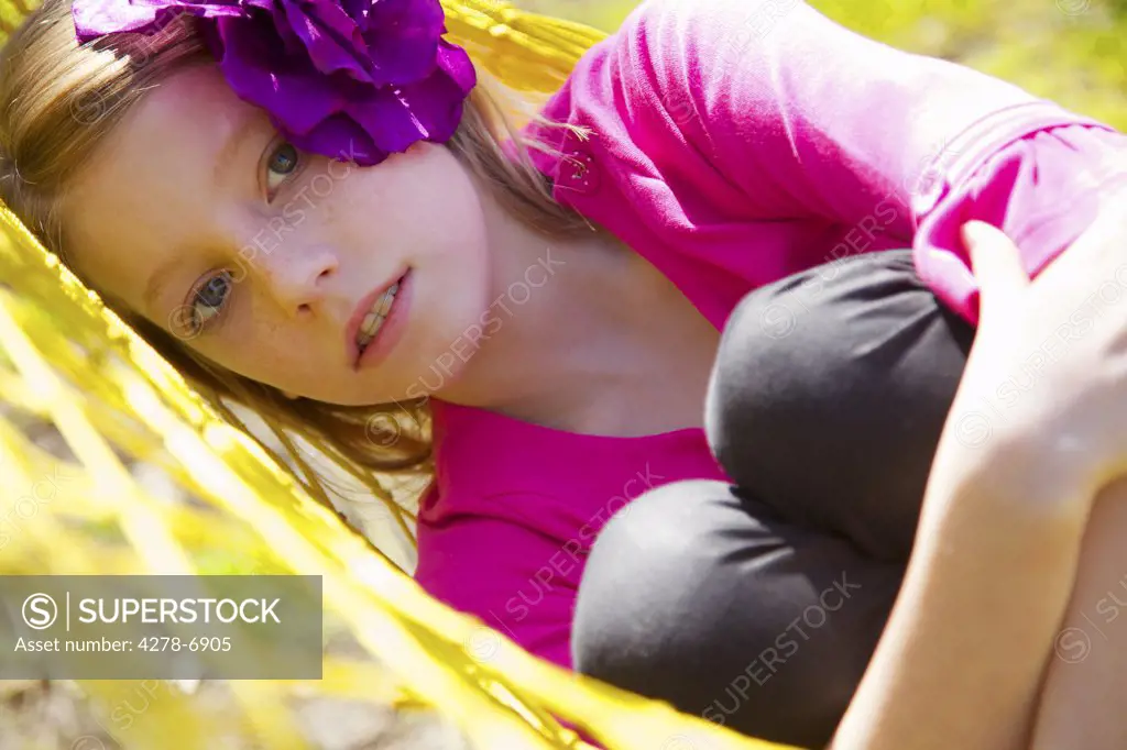 Close up of a girl lying on a hammock hugging her knees