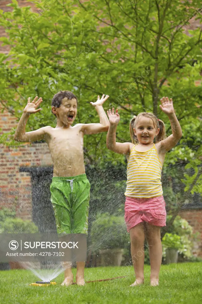 Boy and Girl Playing with Sprinkler