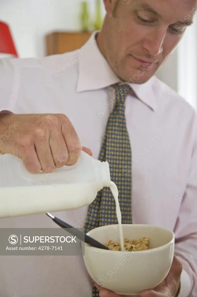 Businessman Pouring Milk into Bowl of  Cereal