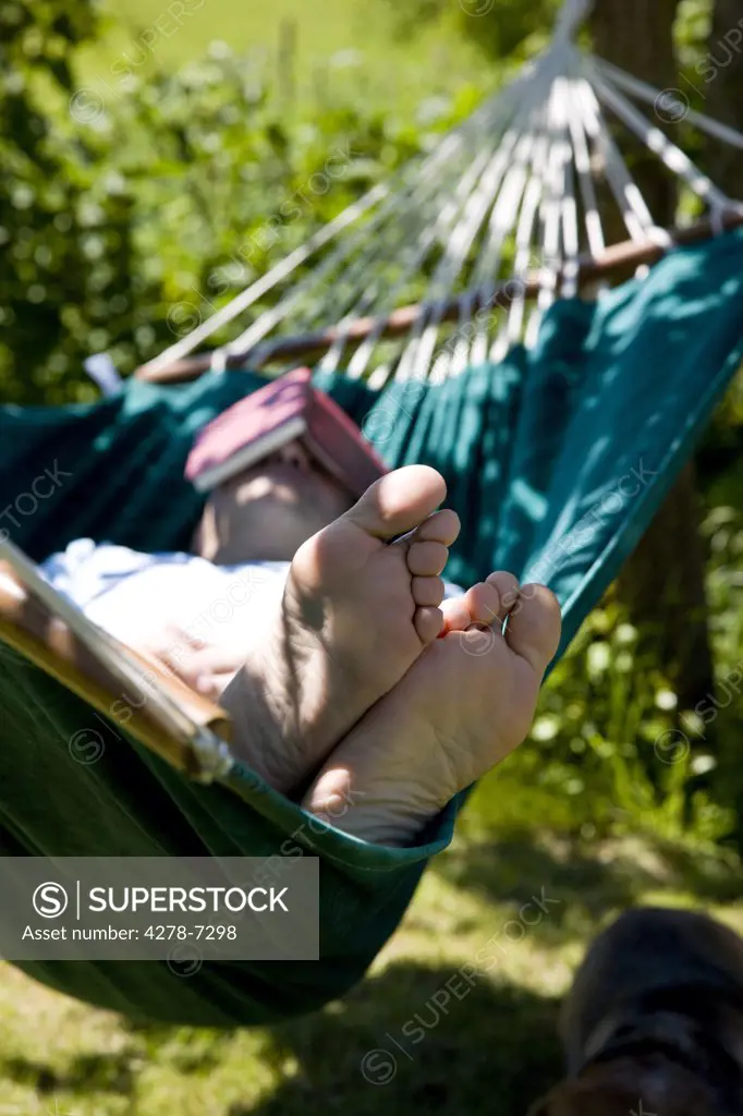 Man Sleeping on Hammock with Book over Face