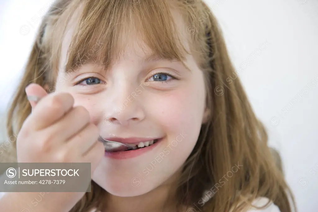 Young Girl Eating with Dessert Spoon