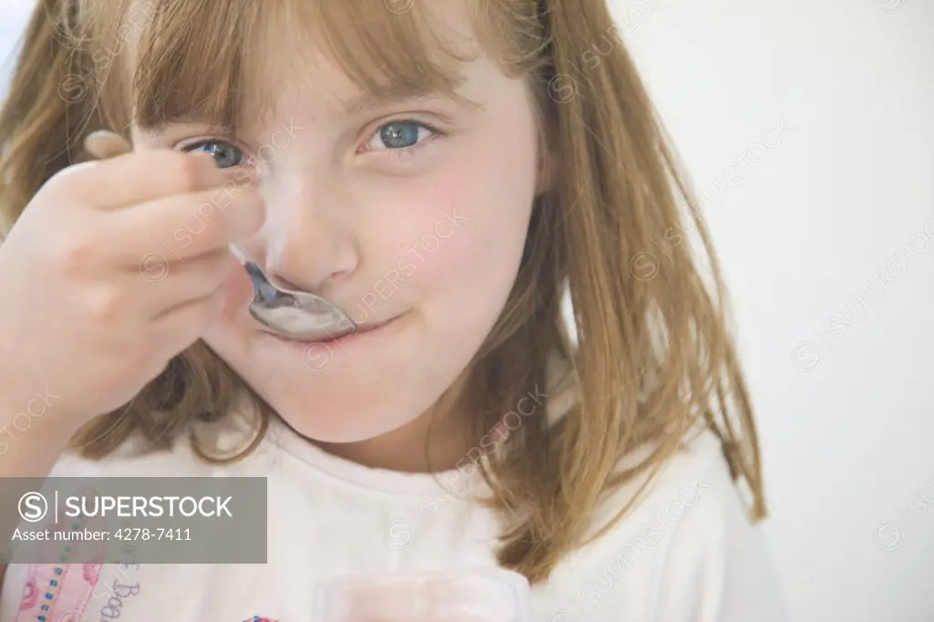 Young Girl Eating with Dessert Spoon