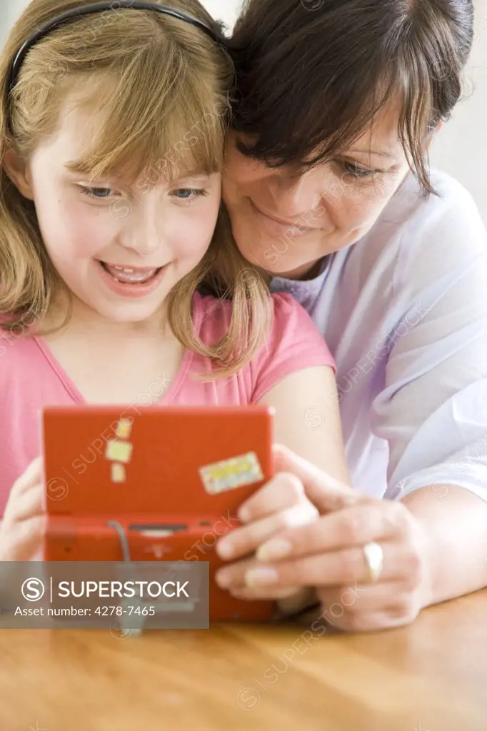 Mother and Daughter Playing with Handheld Video Game