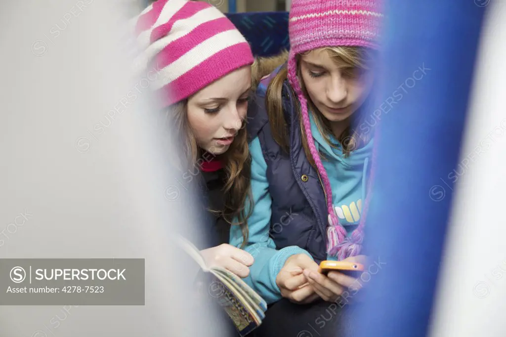 Teenage Girls Sitting on Train Using Smartphone