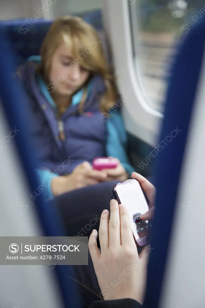 Teenage Girls Sitting on Train Using Smartphones