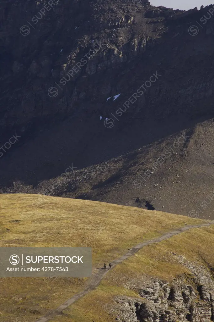 Alpine Landscape with Two Backpackers Walking on Mountain Trail