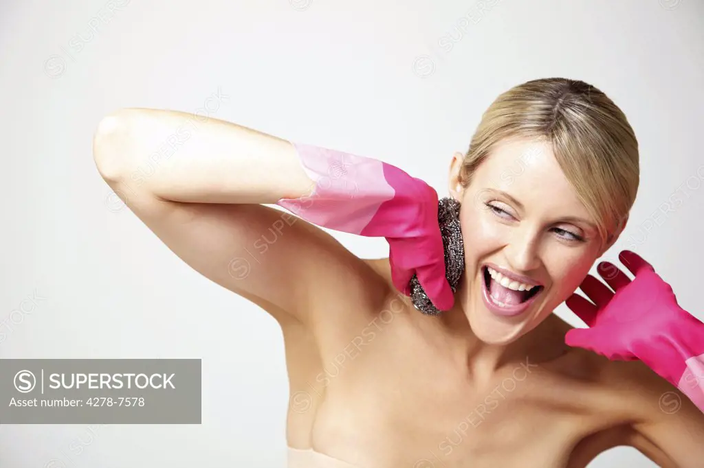 Woman Wearing Bright Pink Rubber Gloves Holding Pan Scourer against Face