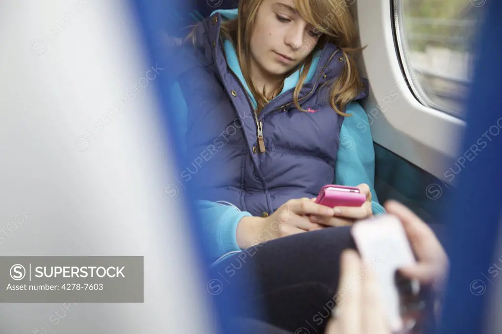 Teenage Girls Sitting on Train Using Smartphones