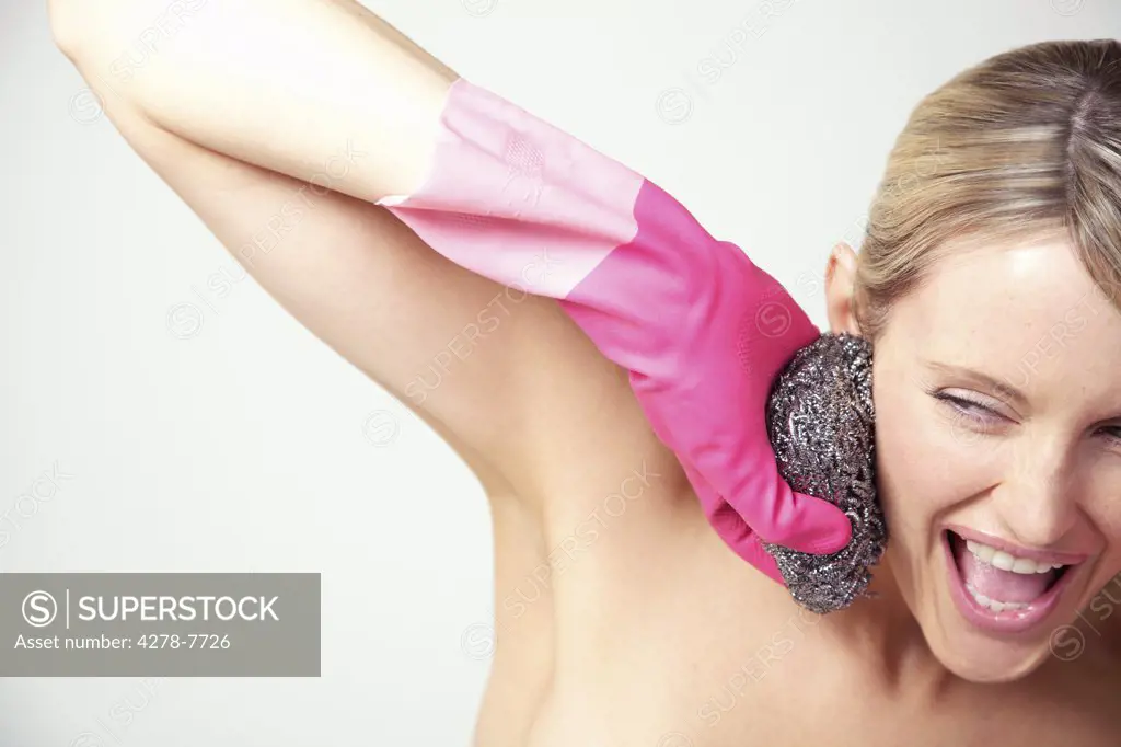 Woman Wearing Bright Pink Rubber Gloves Holding Pan Scourer against Face