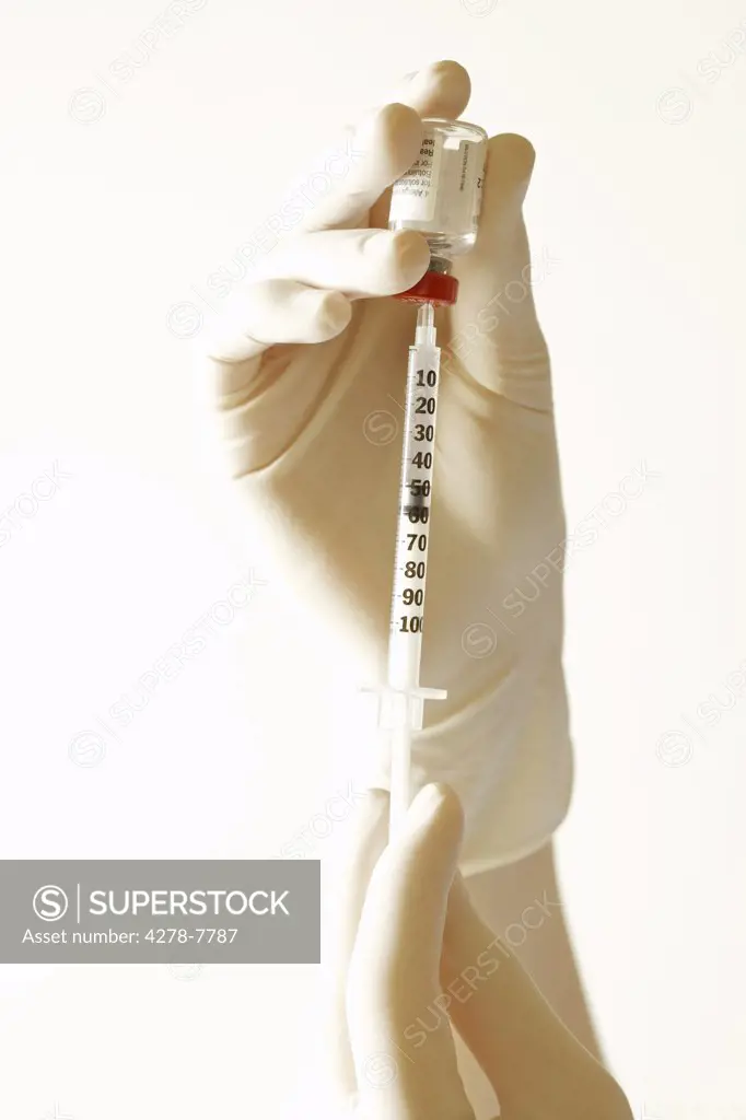 Hand Inserting Hypodermic Needle into Vial