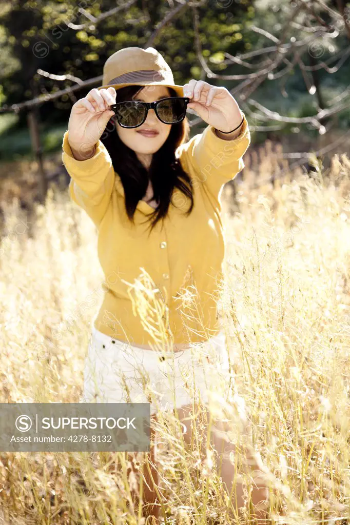 Young Woman Holding Sunglasses in front of Face