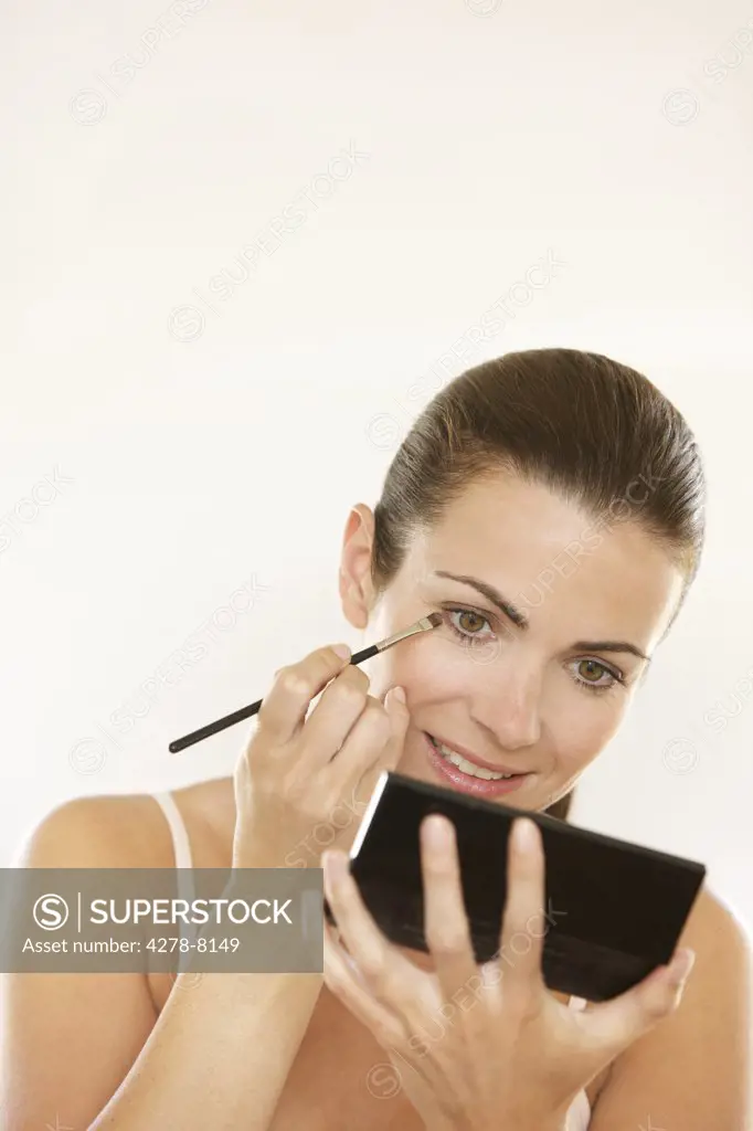 Woman Holding Handheld Mirror Applying Eyeshadow