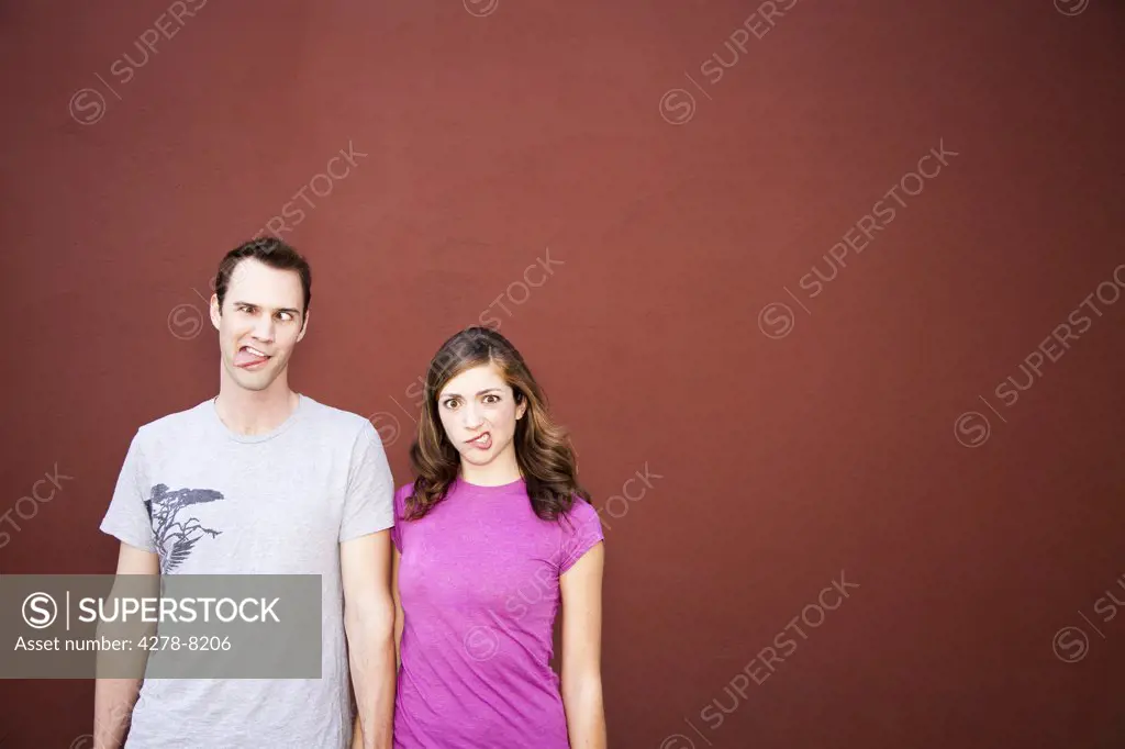 Young Couple Standing Side By Side Making Funny Faces