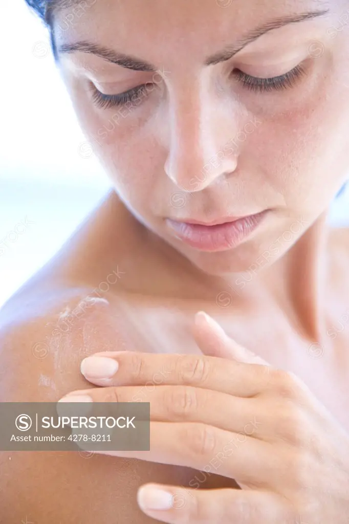 Young Woman Applying Body Lotion on Shoulder