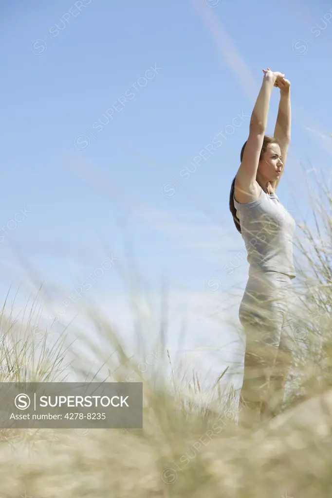 Woman Stretching Arms on Sand Dune