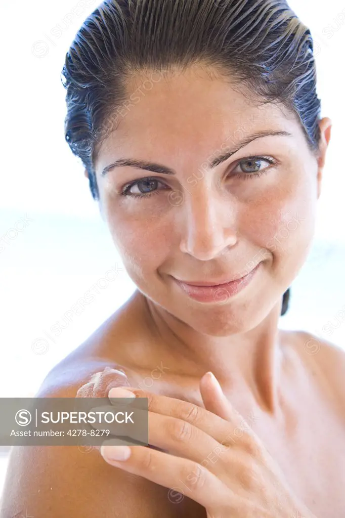 Smiling Woman Applying Body Lotion on Shoulder