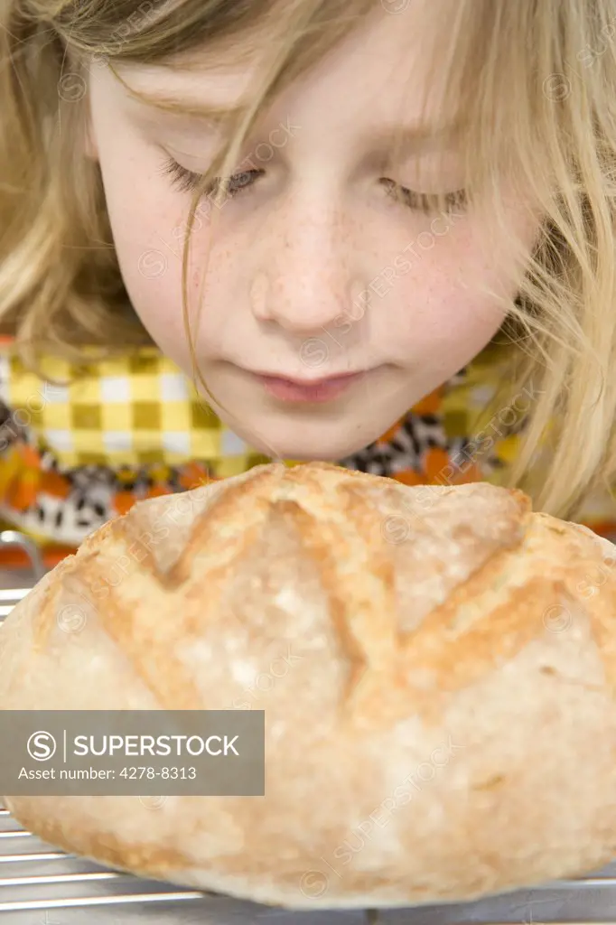 Young Girl Smelling a Loaf of Bread