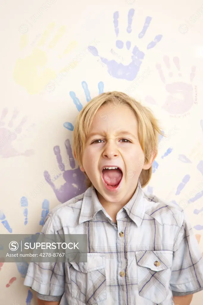 Screaming Boy Standing in front of Wall Covered in Handprints