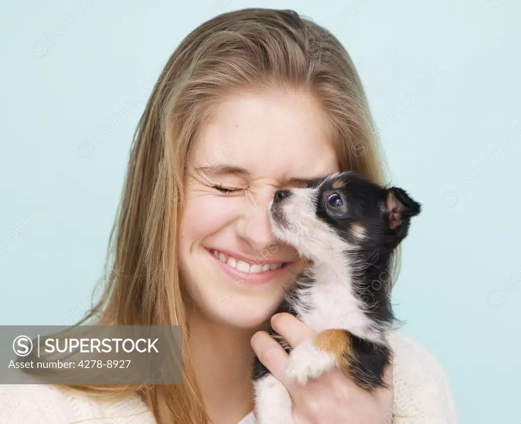 Smiling Teenage Girl Hugging Tiny Puppy