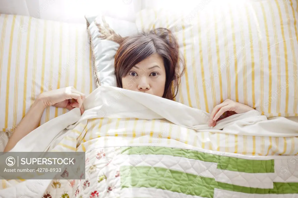 Woman in Bed Peering out from Under Bed sheet