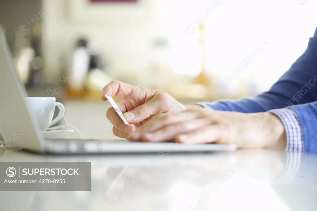 Close up of Man's Hands Holding Credit Card and Using Laptop