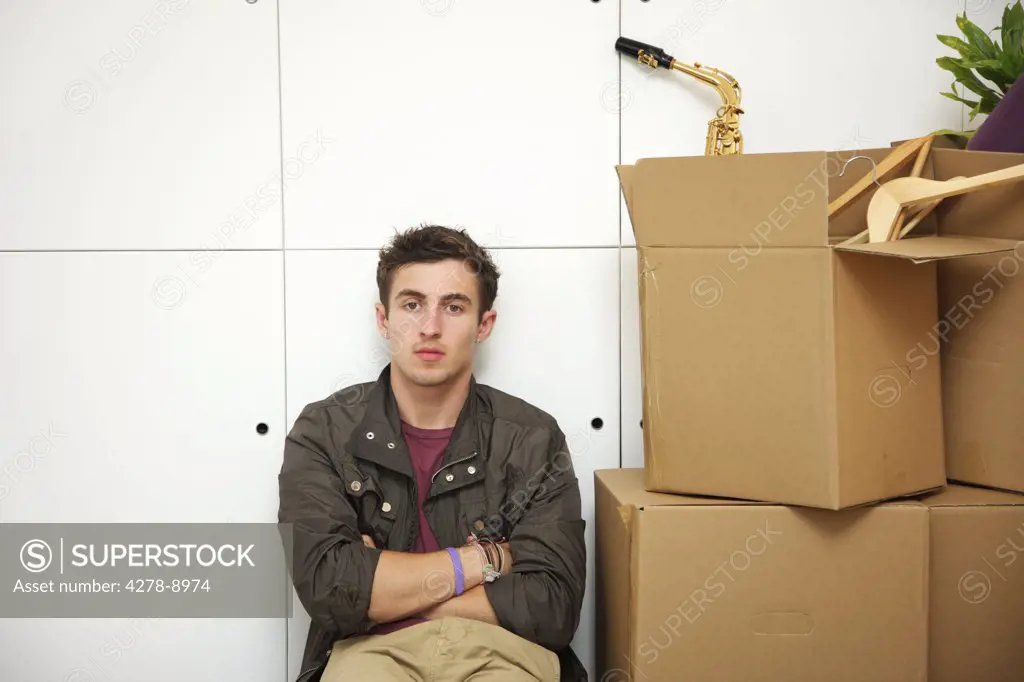 Man Sitting with Arms Crossed by Cardboard Boxes