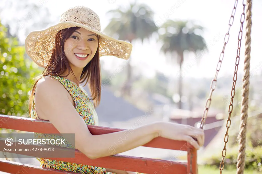 Smiling Woman Wearing Straw Hat Sitting on Porch Swing