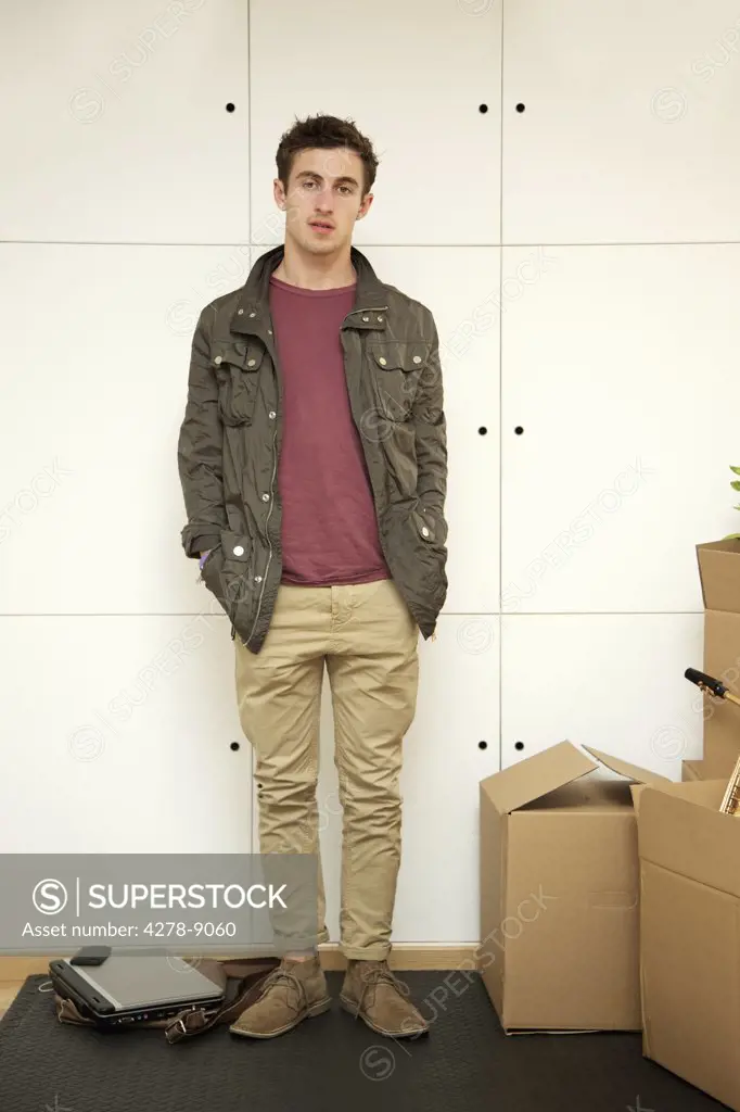Man Standing with Hands in Pockets by Cardboard Boxes