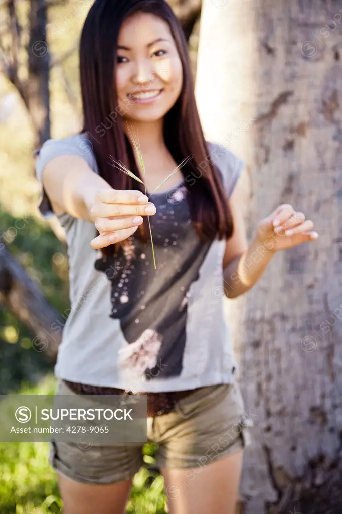 Smiling Young Woman Holding a Piece of Grass