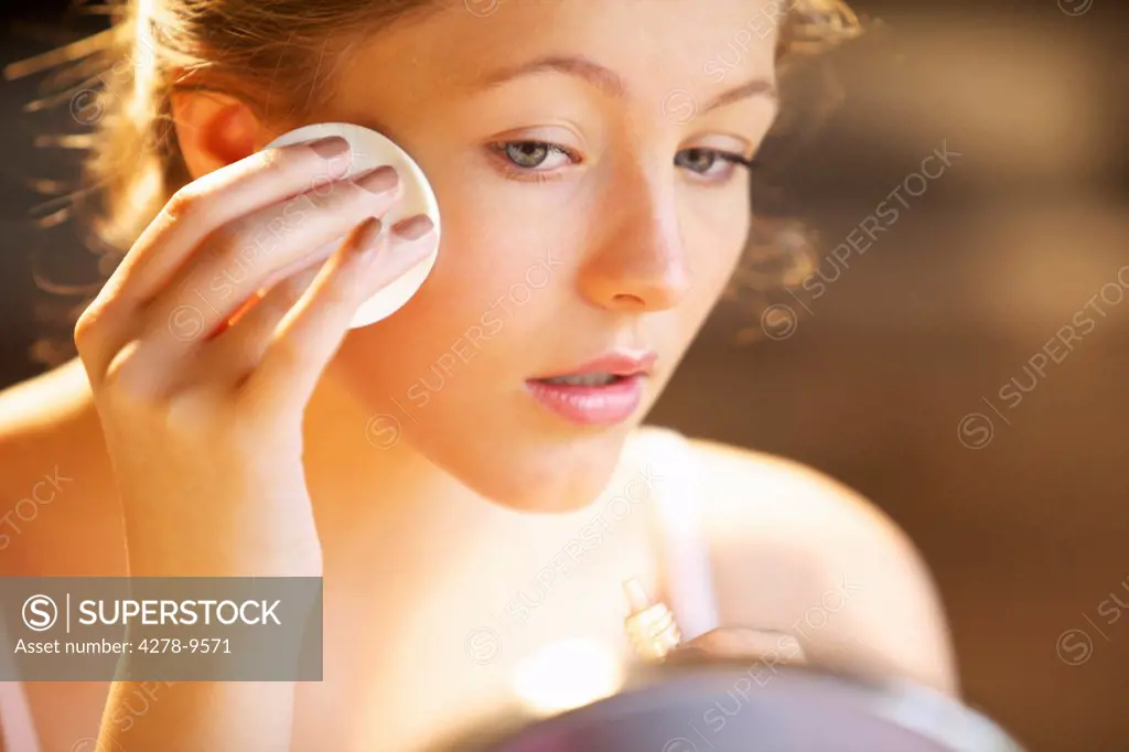 Young Woman Applying Makeup with Cotton Pad