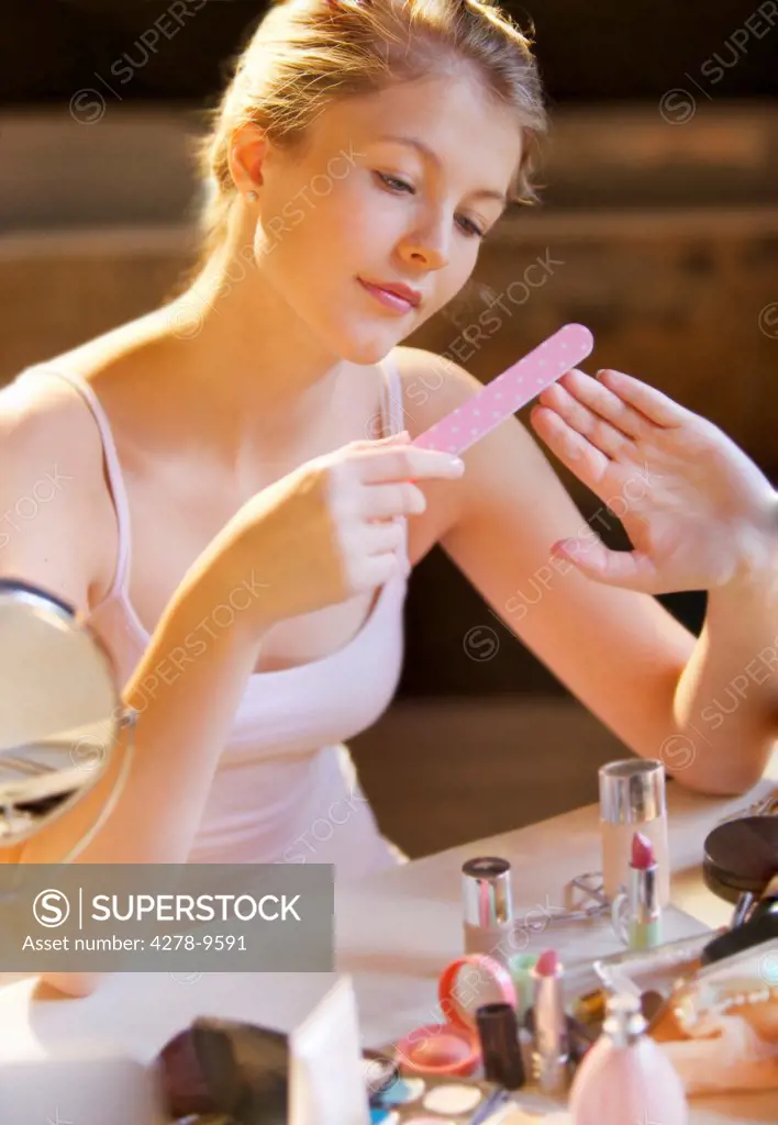 Young Woman Filing her Nails at Dressing Table