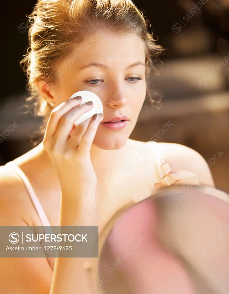 Young Woman Applying Makeup with Cotton Pad