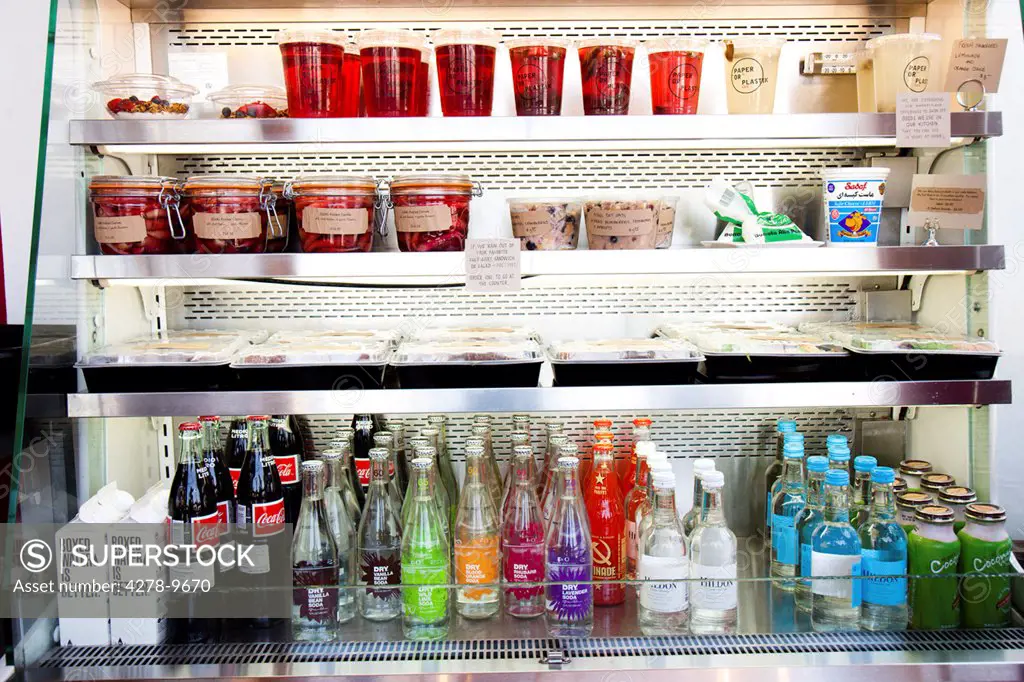 Shop Refrigerator Shelves Stacked with Food Containers and Soft Drink Bottles